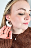 Medium hoop earrings that are white and fluffy are worn by a girl with a brown sweater on - Fleece Chic