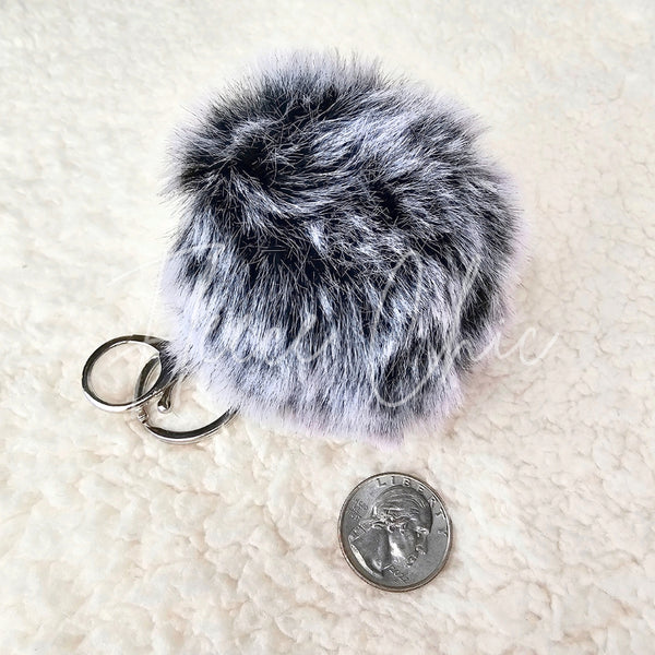 A close-up showing a fur bag charm and keychain's size compared to a quarter - Fleece Chic