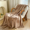 A plush blanket that is tan is draped over a white fluffy chair - Fleece Chic