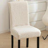 A white sherpa chair cover on a chair, providing a plush and cozy appearance while adding protection - Fleece Chic