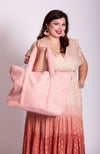 A woman holding a pink zippered tote bag by Fleece Chic while wearing a pink and coral ombre dress.