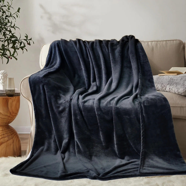 A plush blanket that is black is draped over a light beige couch - Fleece Chic