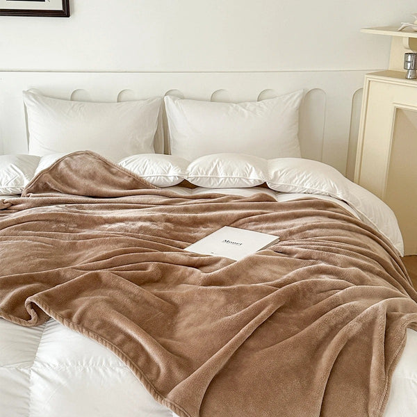 A plush blanket that is tan is draped over a white bed - Fleece Chic