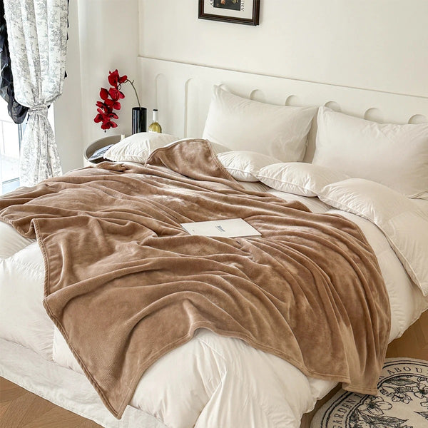 A plush blanket that is tan is draped over a white bed - Fleece Chic