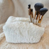 A small cosmetic fur bag with makeup brushes sticking out of it - Fleece Chic