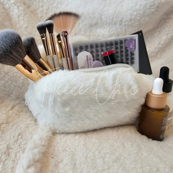 A fur bag that is white is displayed open with various makeup and applicators sticking out of it - Fleece Chic