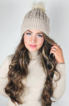 A woman wears a fleece beanie with a cute pom pom on it by Fleece Chic paired with a cotton sweater.