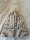 A beige fleece beanie with cozy sherpa lining is displayed with a fun pom pom - Fleece Chic