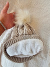 A beige fleece beanie by Fleece Chic has its cozy lining displayed.