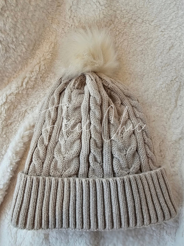 A beige fleece beanie with cozy sherpa lining is displayed with a fun pom pom - Fleece Chic