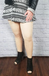 Fleece lined tights in beige with plush lining are paired with a geometric patterned skirt, Fleece Chic's Vegan Leather Jacket with Fleece Lining, and black booties.