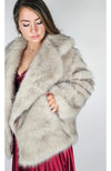 A woman wears a fox fur coat and tucks her hand into one of its pockets - Fleece Chic