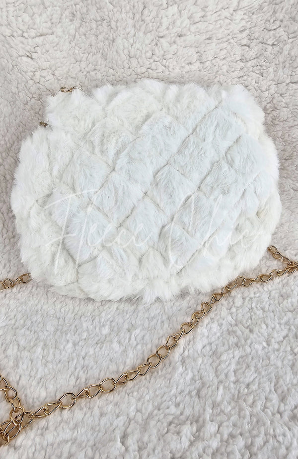 A close-up detailed image of a beautiful fur purse that is white with a golden chain by Fleece Chic shown from its rear view.