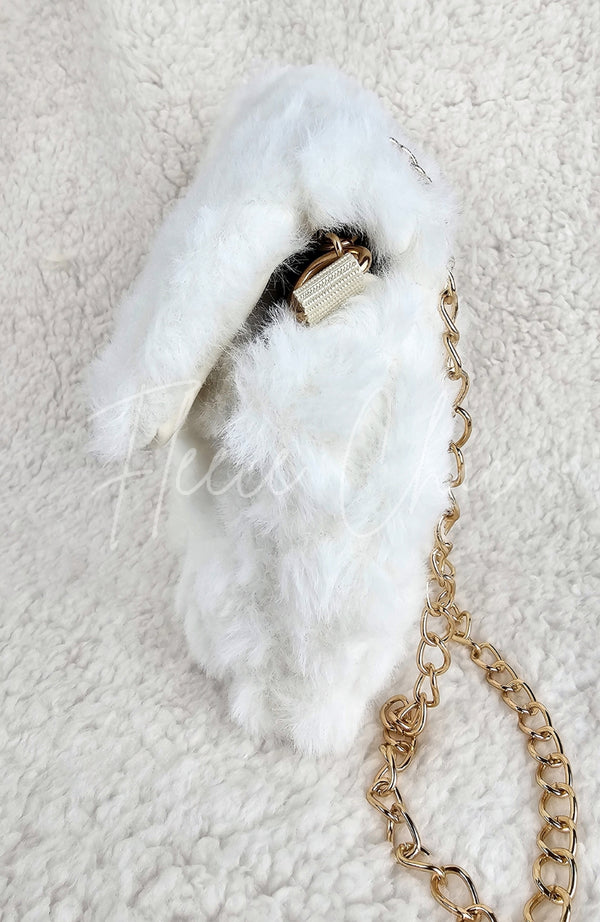 A close-up detailed image of a beautiful fur purse that is white with a golden chain by Fleece Chic shown from its side profile.