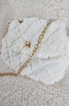 A close-up detailed image of a beautiful fur purse that is white with a golden chain by Fleece Chic