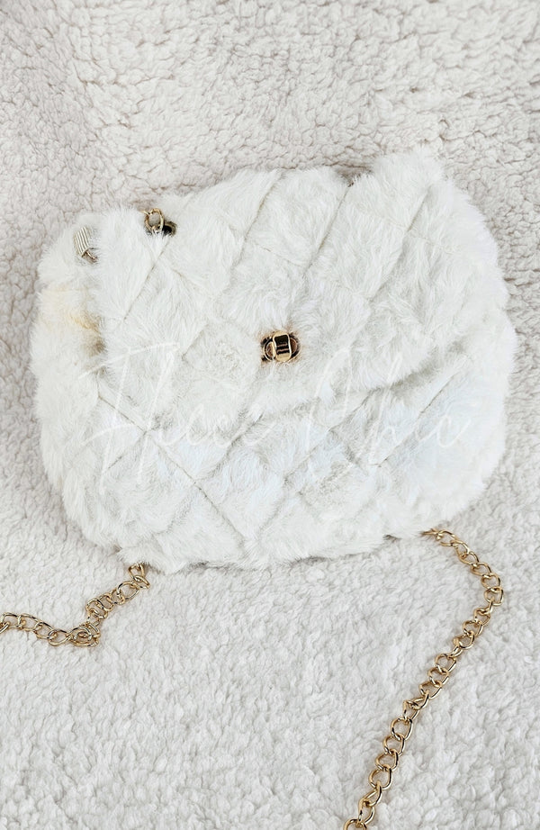 A detailed close up of a fur purse that is white with diamond patterns on it and golden details - Fleece Chic
