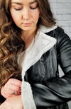 A Vegan Leather Jacket has its plush fleece collar and sleeve displayed for the camera - Fleece Chic