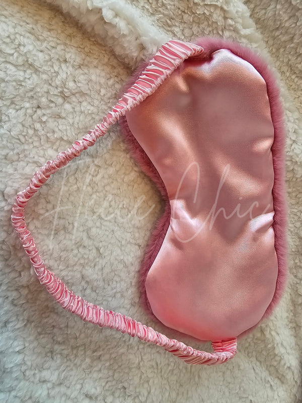 The backside of a pink Faux Fur Sleep Mask by Fleece Chic on a beige sherpa background.