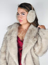 A woman poses wearing fur earmuffs, a fox fur coat, and a maroon silk dress - Fleece Chic