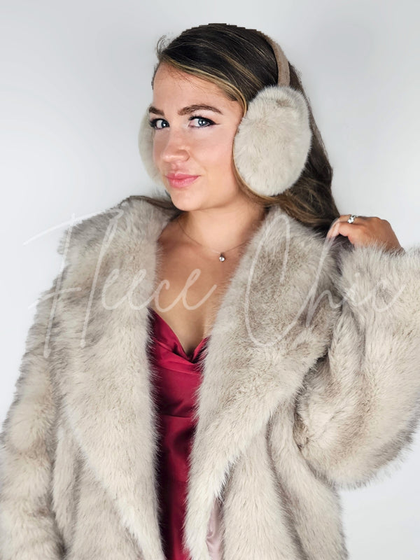 A woman poses wearing fur earmuffs, a fox fur coat, and a maroon silk dress - Fleece Chic