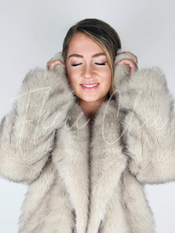 A woman poses wearing fur earmuffs paired with a fox fur coat by Fleece Chic.
