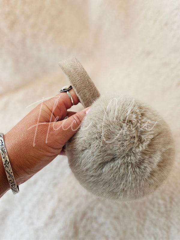 Light brown fur earmuffs by Fleece Chic are held up for a closer look.