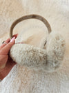 A woman holds fur earmuffs by Fleece Chic.