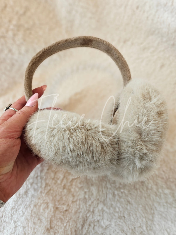 A woman holds fur earmuffs by Fleece Chic.