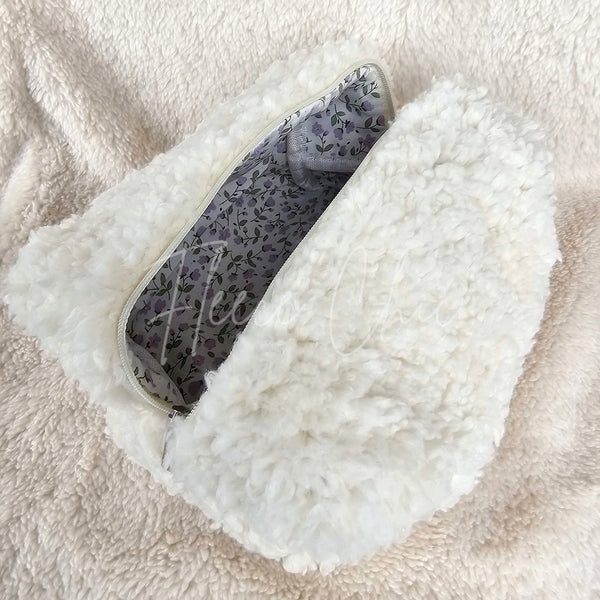 A close-up picture of a white sherpa bag with a pretty purple flower lining - Fleece Chic