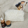A Sherpa bag with a flower lining is pictured with various makeup brushes and face ointments - Fleece Chic