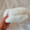 A small cosmetic fur bag that is white and is made with faux fur is displayed zipped closed - Fleece Chic