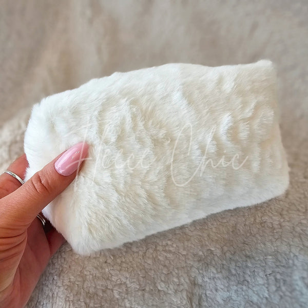A fur bag that is white and is made with faux fur is held up on display - Fleece Chic