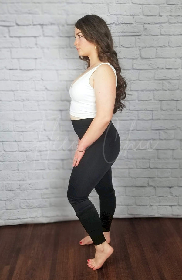 A woman wears opaque fleece lined tights that are black paired with a white crop top - Fleece Chic