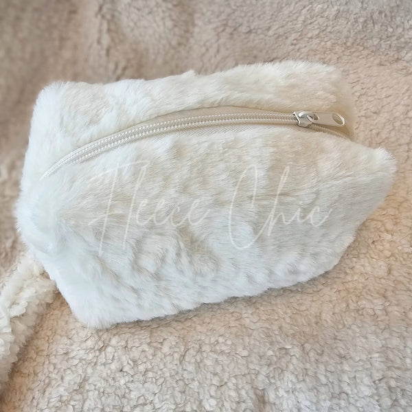 A fur bag that is white and is made with faux material is displayed zipped closed - Fleece Chic