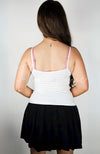 A woman displays the back of a white Thermal Tank and black Twirl Skirt by Fleece Chic.