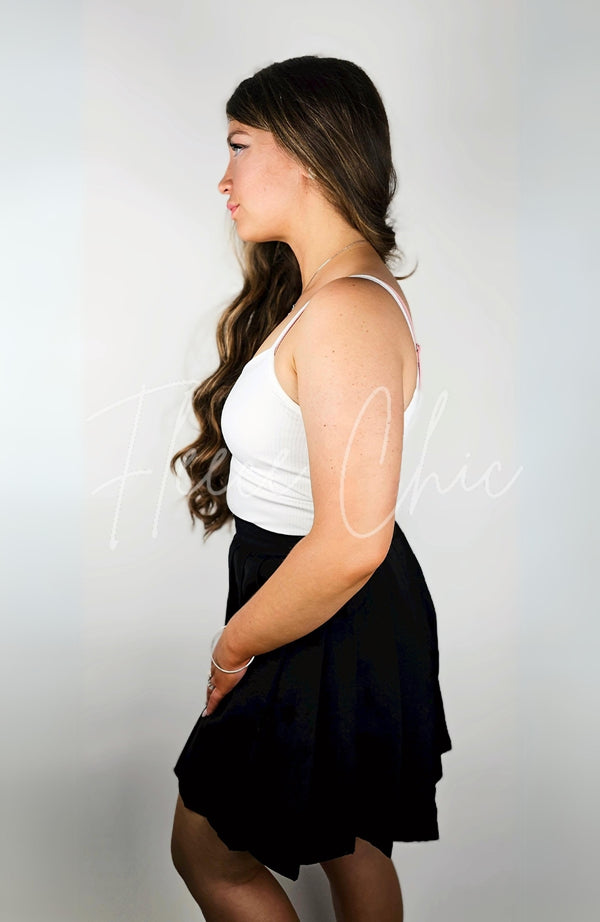 A woman displays the side profile of a white Thermal Tank and black Twirl Skirt by Fleece Chic.