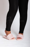 A woman in black winter leggings wears pink fuzzy slides by Fleece Chic.