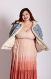 A plus size model wears a lined trucker jacket with a fur interior that is reversible paired with a pink and orange ombre dress - Fleece Chic