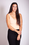 A woman wears a beige thermal tank top with lace paired with black knit pants by Fleece Chic.