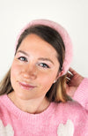A pink fur headband is modeled by a woman in a pink sweater - Fleece Chic.