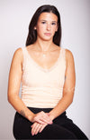 A woman sits with her hands crossed over her legs while wearing a thermal tank top with lace by Fleece Chic.