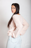 A women facing away turns her head toward the camera while wearing a light pink fuzzy sweater by Fleece Chic.