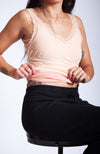 A woman wears a beige thermal tank top while sitting down and shows off its fleece interior - Fleece Chic