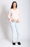 A woman wears a pink fuzzy sweater that has a v neck along with light blue jeans and black winter clogs by Fleece Chic.