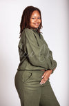 A woman smiles while turned away from the camera wearing a green sweat set by Fleece Chic.