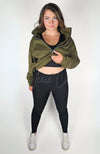 A woman wears a black pair of cozy leggings with a plush lining and the green top of the Effortlessly Chic Tracksuit by Fleece Chic.