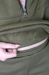 A woman wearing a fleece sweatshirt and fleece sweatpants displays the inside fuzzy lining of the top.