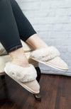 Faux fur slippers in beige with a plush collar are modeled by a woman sitting in a chair - Fleece Chic