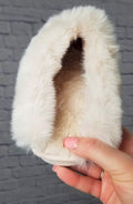 Plush slippers with a long faux fur collar are held up to display their soft inside - Fleece Chic