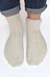 Beige quarter socks with one rolled down partly to show off its plush interior worn with rolled-up jeans on a white background - Fleece Chic